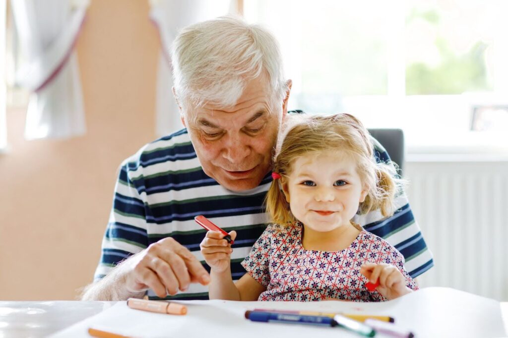 Grandfather coloring with his granddaughter